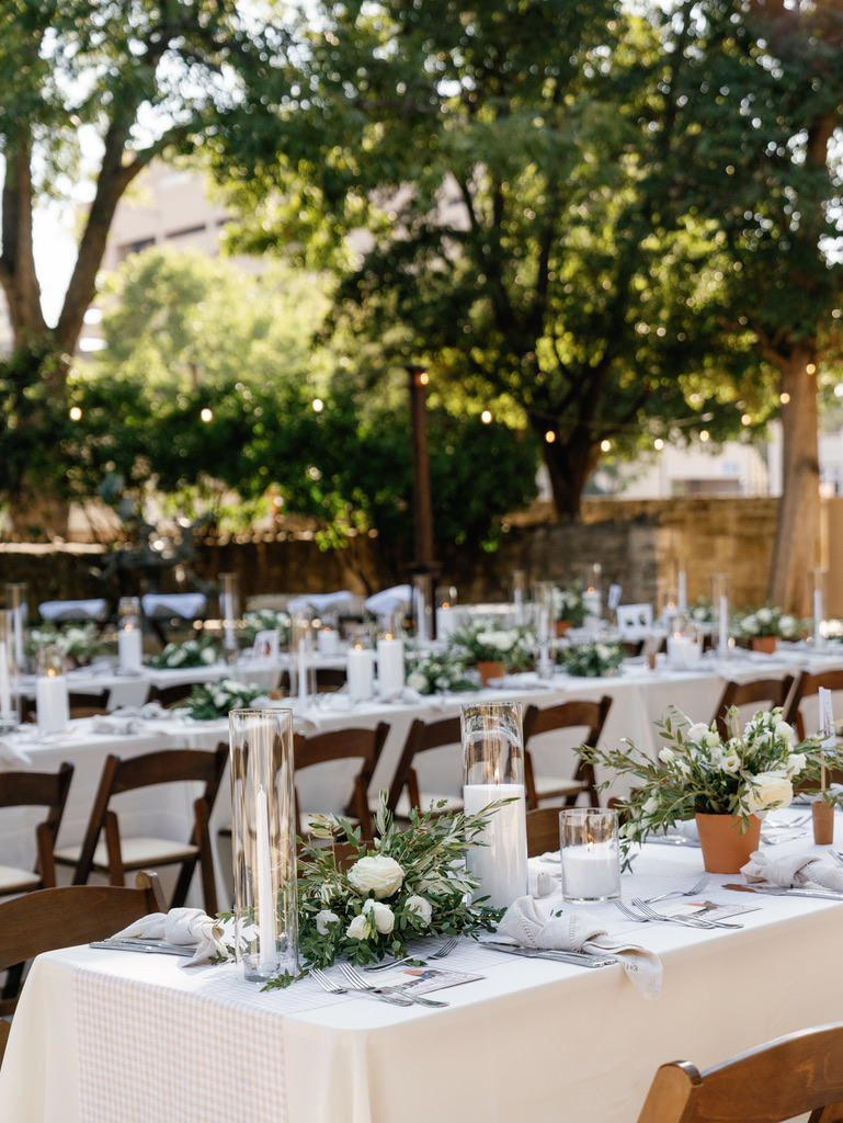 Outdoor wedding reception setup with greenery and wood tables at a Central Texas venue, styled by a wedding planner.