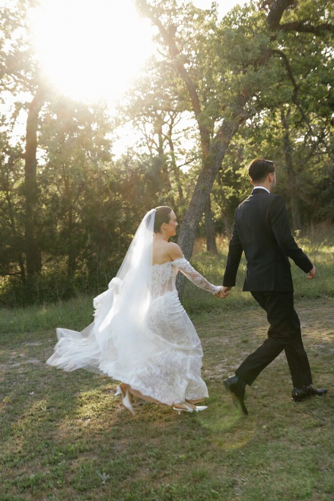 Bride and groom walking through the trees at The Grand Lady, a Hill Country wedding venue.