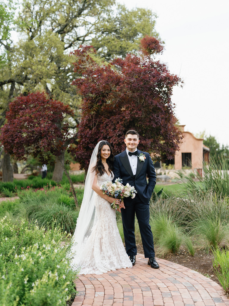 Bride and groom standing on brick path at Camp Lucy, a popular Central Texas wedding venue.