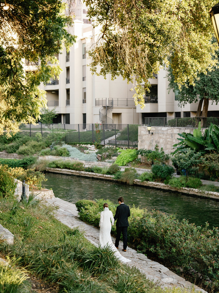 Bride and groom walking along a river path at a Central Texas wedding venue, planned by a local wedding planner.