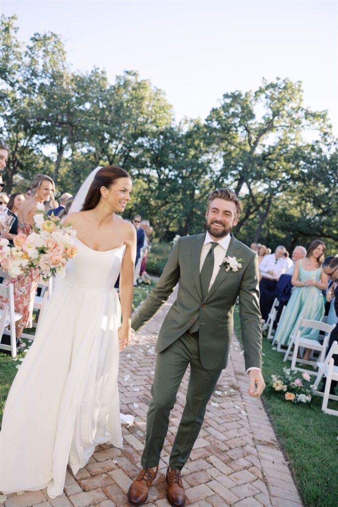 Newlyweds walk the aisle after outdoor ceremony at The Grand Lady, a Central Texas wedding venue.