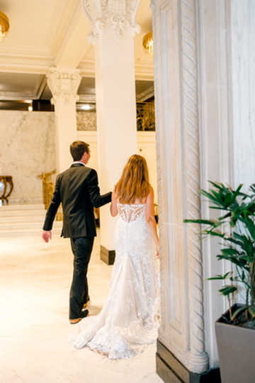 Bride and groom entering elegant venue with marble columns, supported by a Central Texas wedding planner.