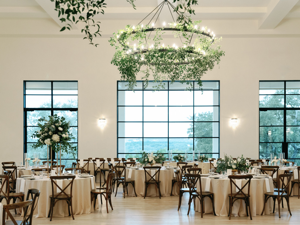 Modern indoor reception with greenery chandeliers at The Arlo, styled by a Central Texas wedding planner.