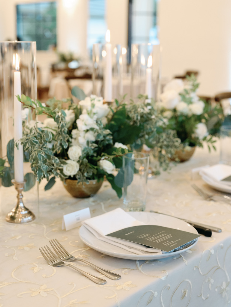 Elegant table setting with greenery and candles at a Central Texas wedding venue reception, styled by a wedding planner.