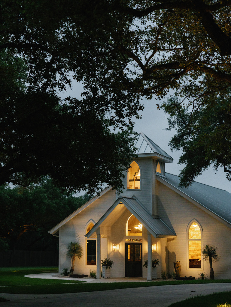 White chapel at The Chandelier of Gruene, a Central Texas wedding venue, illuminated at night.