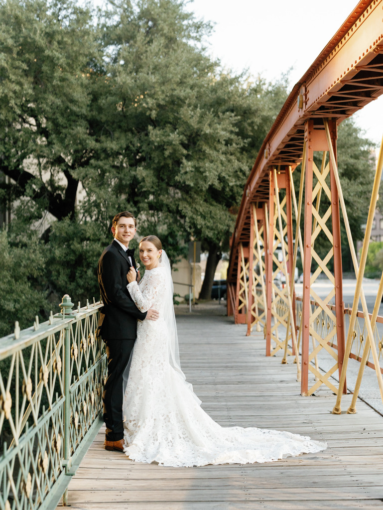 Bride and groom posing on a scenic bridge at a Central Texas wedding venue, planned by a local wedding planner.