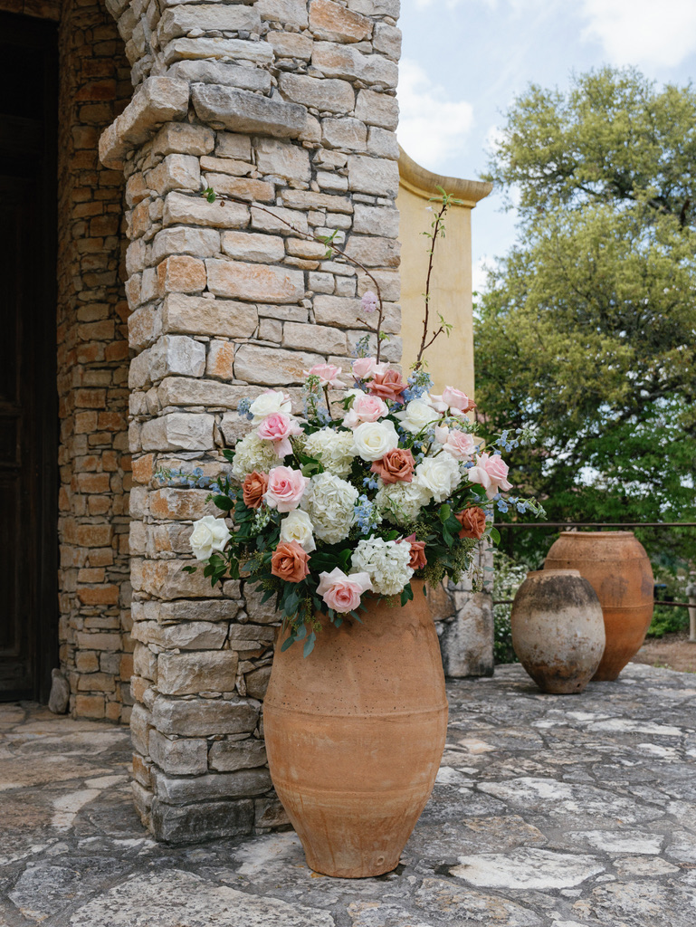 Large floral arrangement in terracotta urn at Camp Lucy, styled by a Central Texas wedding planner.