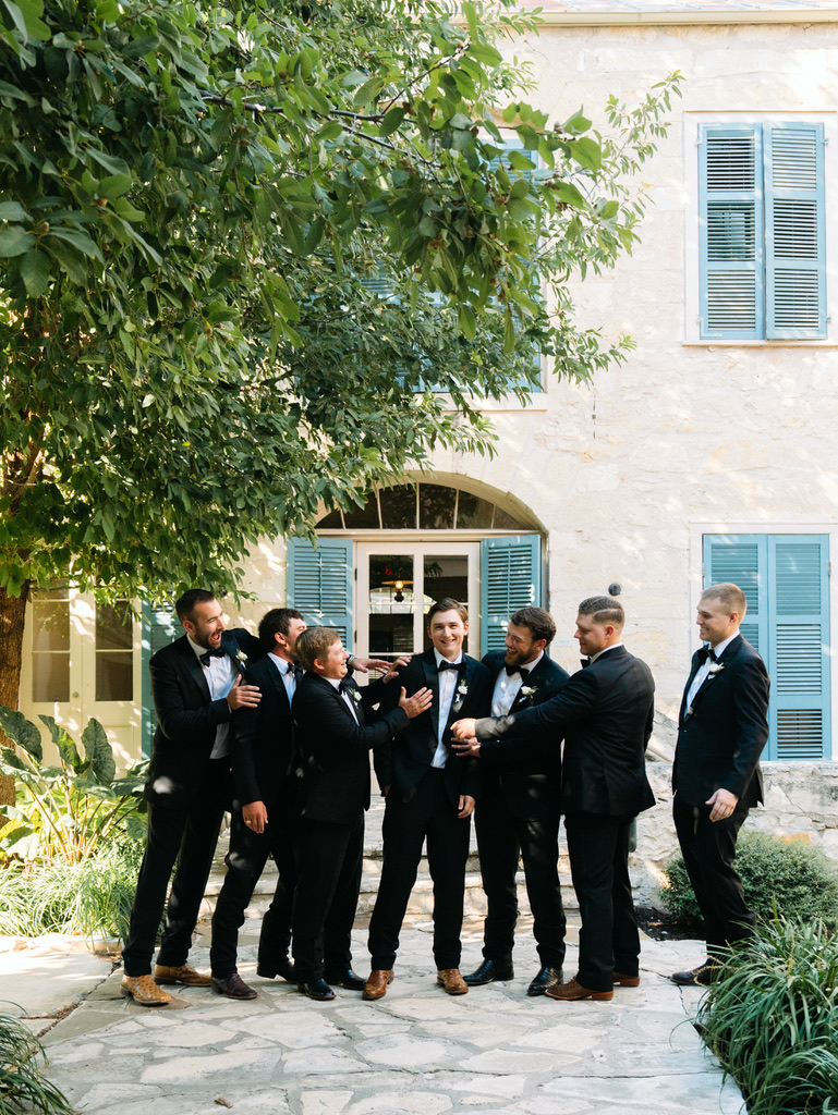 Groom and groomsmen sharing a fun moment at a Central Texas wedding venue, coordinated by a Hill Country planner.