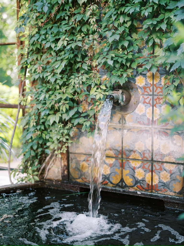Spanish-style fountain with colorful tiles and ivy, adding charm to a Central Texas wedding venue courtyard.