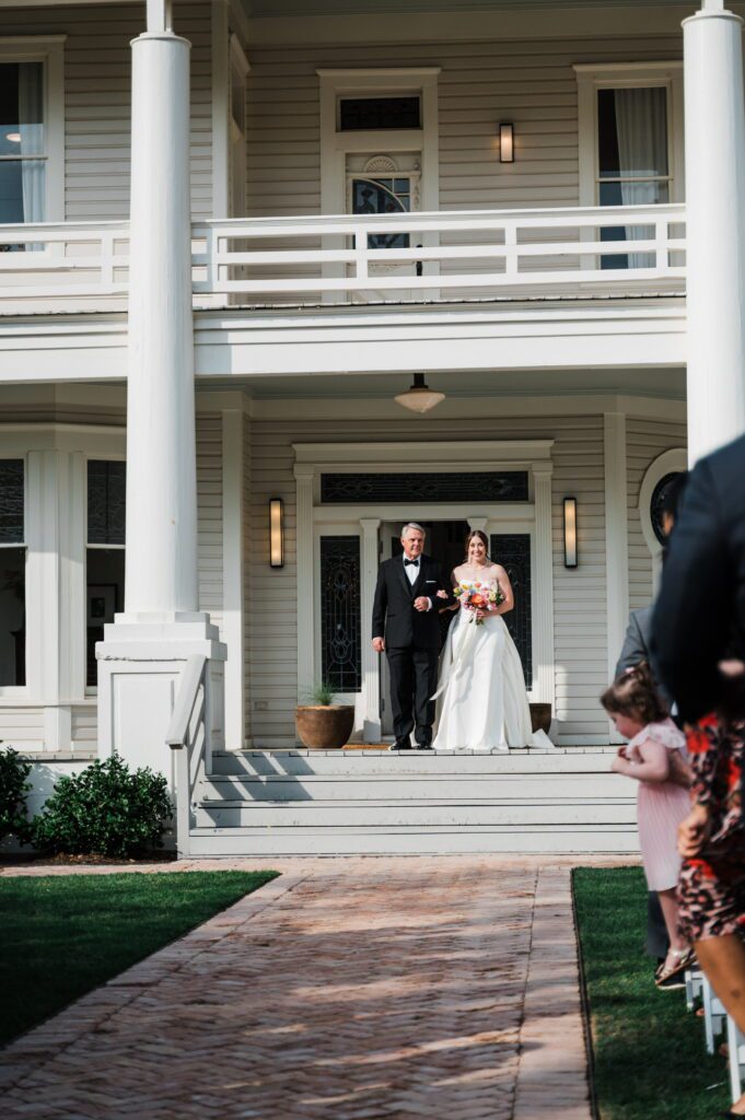 Bride walking out of historic mansion at The Grand Lady, a Central Texas wedding venue with timeless charm.