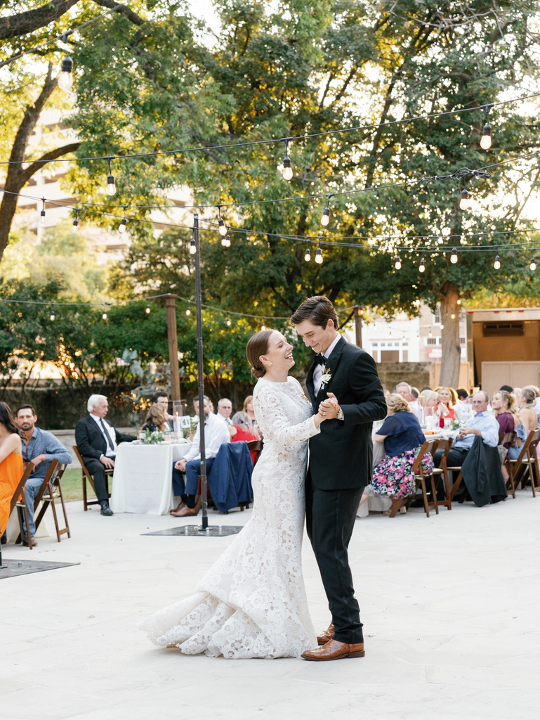 Outdoor first dance under string lights at a Central Texas wedding venue, with planning by a Hill Country wedding planner.