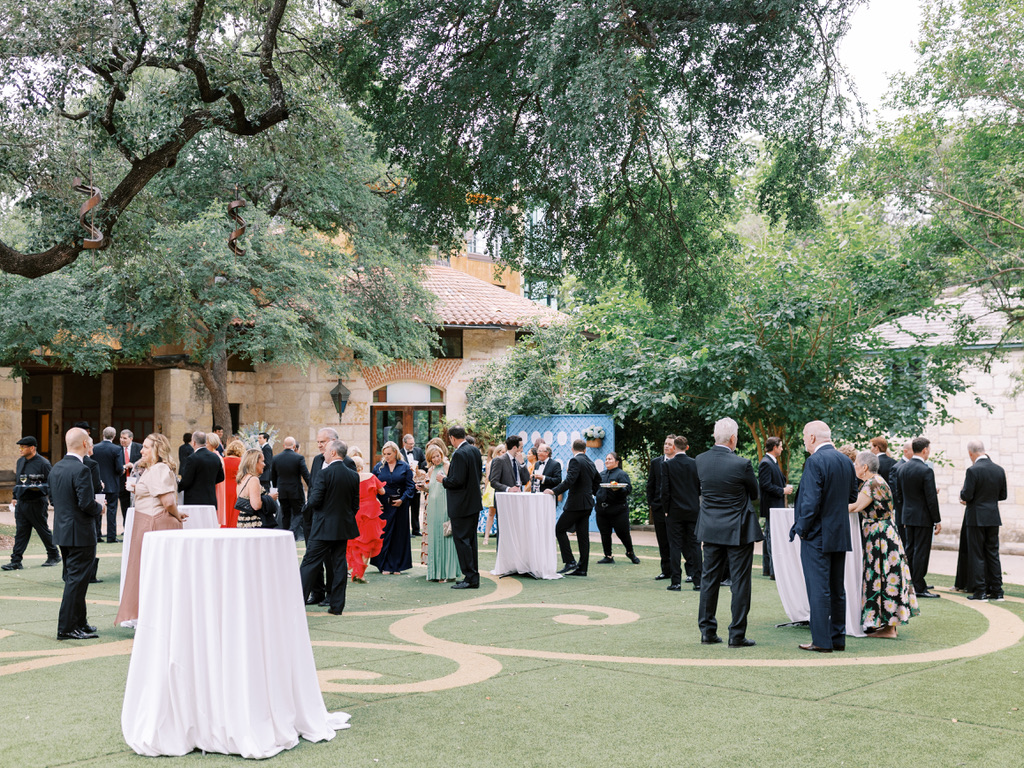 Wedding guests enjoying outdoor cocktail hour under trees at a Central Texas venue, with planning by Lila Lane Events.