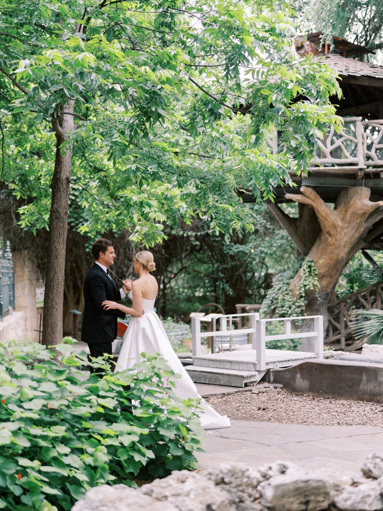 Bride and groom walking near a garden bridge at a Central Texas wedding venue, planned by a Hill Country wedding planner.