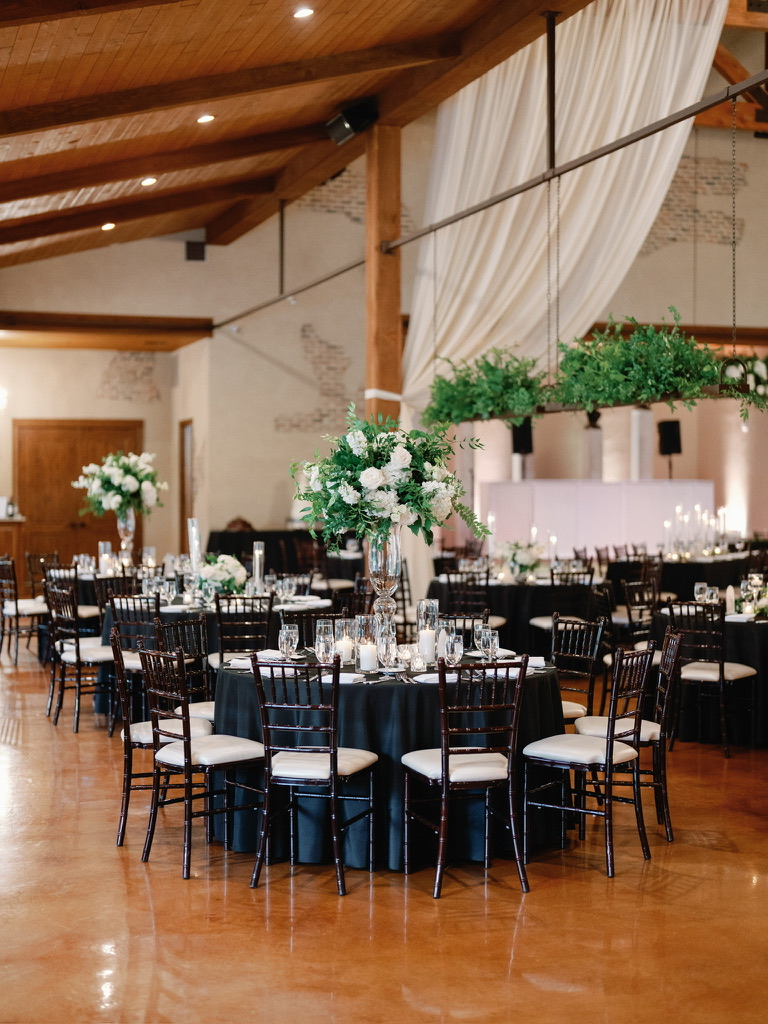Indoor reception setup with black linens and greenery at The Chandelier of Gruene, styled by a local wedding planner.