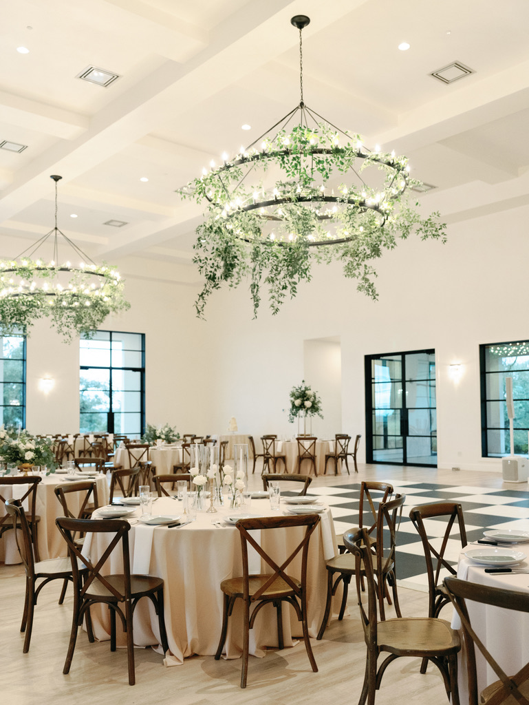 Indoor reception space with greenery chandeliers at a modern Central Texas wedding venue.