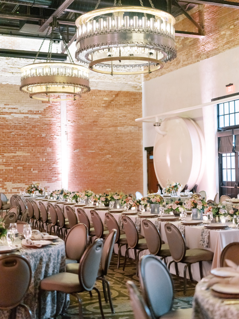 Elegant wedding reception setup with long tables, blush florals, and chandeliers at a Central Texas wedding venue