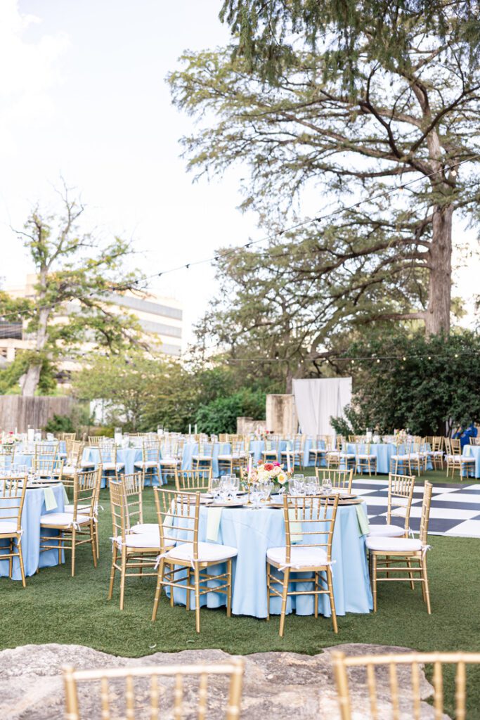 Outdoor reception with blue and gold table settings at a Central Texas wedding venue, styled by a Hill Country wedding planner.