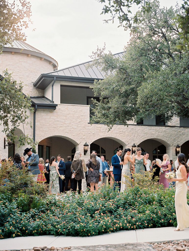 Wedding guests mingling outdoors during cocktail hour at a Hill Country venue | planned by San Antonio wedding planner