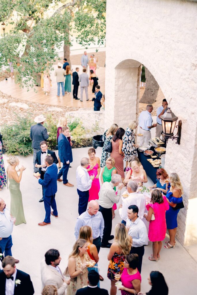 Guests enjoying cocktails and appetizers in a shaded courtyard