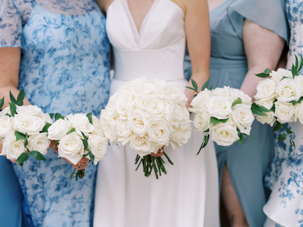 Close-up of bride holding large white rose bouquet surrounded by bridesmaids’ bouquets, an example of floral costs in a realistic wedding budget Texas celebration.