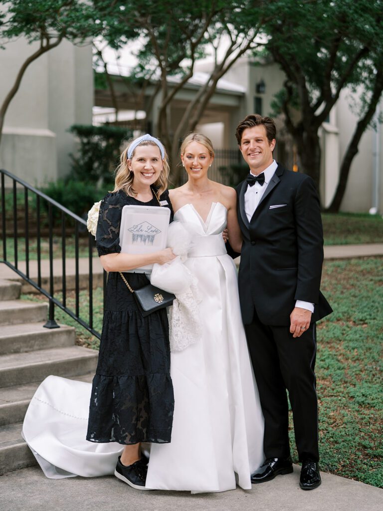 Hill Country wedding planner Ashtyn Burttschell of Lila Lane Events smiling with a newlywed couple in elegant black-tie attire, representing the value of hiring a planner when creating a realistic wedding budget.