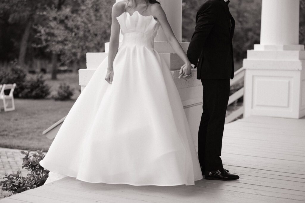 Black and white image of couple holding hands on porch at Austin wedding venue